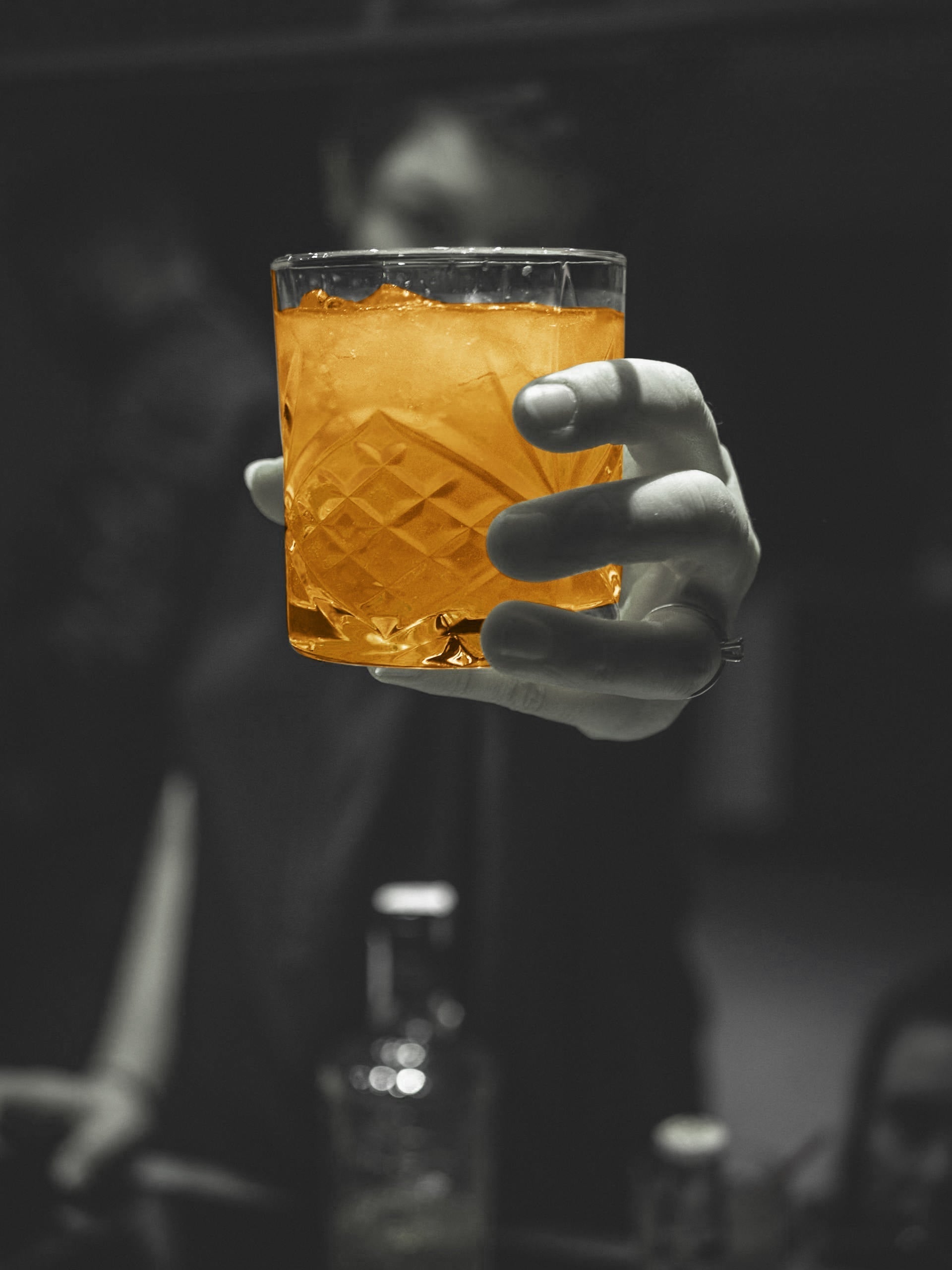 Hand holding an ANZA Beauty Beverage collagen drink in a crystal glass against a dark editorial background